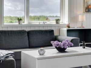 ein Wohnzimmer mit einem Sofa und einem Tisch mit lila Blumen in der Unterkunft Holiday Home Gustava - 700m from the sea by Interhome in Neder Lysabild