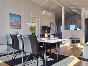 ein Esszimmer mit einem weißen Tisch und schwarzen Stühlen in der Unterkunft Holiday Home Gustava - 700m from the sea by Interhome in Neder Lysabild + 35 Fotos