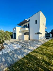 une grande maison blanche avec une cour gazonnée dans l'établissement Luxury Villa Positiva, à Vir