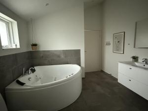 eine weiße Badewanne im Bad mit Waschbecken in der Unterkunft Holiday Home Mauri - 350m from the sea by Interhome in Torsted