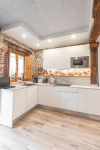 une cuisine avec des armoires blanches et un plancher en bois dans l'établissement El Patio de Vespasiano-Calera- vistas a la iglesia junto al puerto, à Castro Urdiales