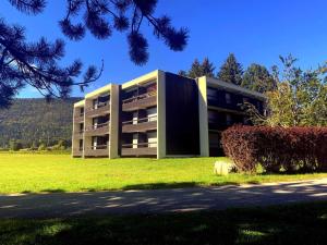 un grand bâtiment avec un champ vert devant lui dans l'établissement Charmant appartement à Autrans, 40m², 4 pers, proche centre et pistes de ski - FR-1-737-30, à Autrans