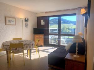 un salon avec une table et un canapé ainsi qu'une chambre avec une fenêtre dans l'établissement Appartement à Autrans, balcon sud, 4 pers, animaux admis, parking à 500m du centre - FR-1-737-38, à Autrans