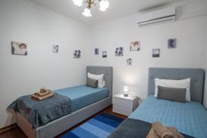 two beds in a bedroom with blue sheets and pictures on the wall at Apartamento Brava JT in Ribeira Brava