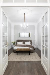 a white bedroom with a bed and a chandelier at Romari Братів Рогатинців 32 in Lviv
