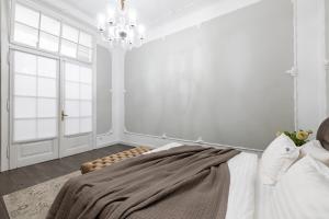 a white bedroom with a bed and a chandelier at Romari Братів Рогатинців 32 in Lviv