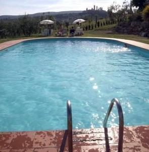 une grande piscine bleue avec deux chaises et des parasols dans l'établissement Schönes Ferienhaus Rosanna, à San Gimignano