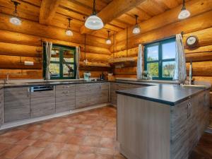 a large kitchen with wooden walls and a large island at Chalet Srub Pohodář by Interhome in Benešov nad Černou