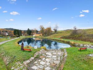 two benches sitting on the grass next to a river at Chalet Srub Pohodář by Interhome in Benešov nad Černou