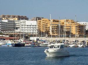 a white boat in the water with buildings in the background at Casa LuLu in San Miguel de Abona