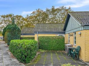 una casa de ladrillo con un banco al lado de un seto en Apartment Felicia - 200m from the sea by Interhome, en Neksø