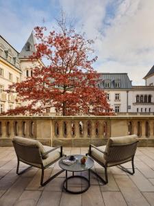 a patio with two chairs and a table and a tree at The Florentin by Althoff Collection in Frankfurt/Main