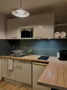 a kitchen with white cabinets and a wooden counter top at Charmant studio in Villeurbanne +3 photos