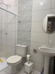 ein weißes Badezimmer mit Toilette und Waschbecken in der Unterkunft Casa de praia in Barra Velha + 8 Fotos