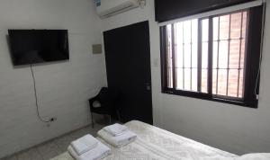 ein Schlafzimmer mit Bett, Fernseher und Fenster in der Unterkunft Lo Nuestro in San Juan