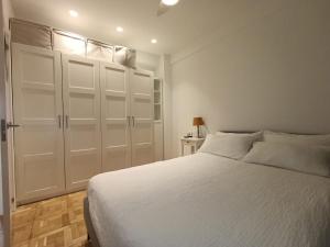 a bedroom with a white bed and white cabinets at Piso en San Sebastián cerca de Anoeta in Loyola