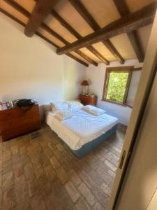 ein Schlafzimmer mit einem Bett, einer Kommode und einem Fenster in der Unterkunft Villa a Capalbio in Carige Bassa