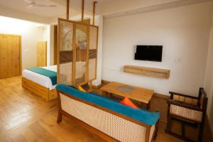 una stanza con un letto, un tavolo e una tv di Kafal Pako Resort - Luxury Mountain View Stay in Mukteshwar a Mukteshwar