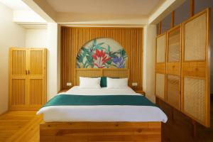 una camera da letto con un letto grande e un dipinto sul muro di Kafal Pako Resort - Luxury Mountain View Stay in Mukteshwar a Mukteshwar
