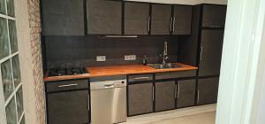 a kitchen with black cabinets and a stove and a sink at Cozy house in Weert in Weert