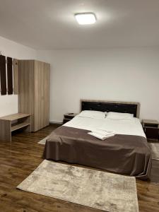 Pensiunea Rustic House Rucăr - Argeș في روكار: غرفة نوم بسرير كبير وأرضيات خشبية