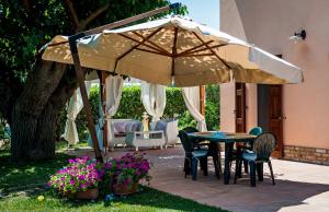 un patio avec une table et des chaises sous un parasol dans l'établissement Villa Mauro, à Mondolfo