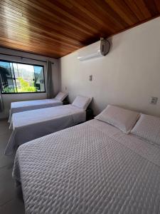 three beds in a room with a window at Pousada Jardim in Lauro Müller