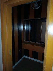 Habitación con TV y puerta a un pasillo. en Single Bedroom Apartment, en Mama