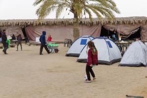 Ein junges Mädchen spielt vor Zelten mit einem Fußball. in der Unterkunft חאן השיירות- אוהלים בדואיים וקמפינג in Midreshet Ben Gurion
