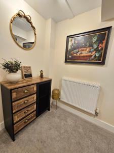 a room with a dresser and a mirror and a painting at Pancinos Guest House Newmarket High Street in Newmarket