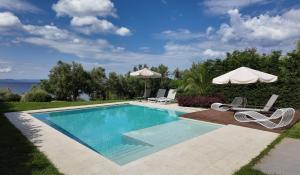 ein Swimmingpool mit zwei Stühlen und einem Sonnenschirm in der Unterkunft Luria Homes in Lagomandra