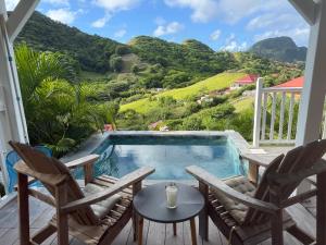 a patio with chairs and a swimming pool with a mountain at Creole Paradise beach wifi in Terre-de-Haut