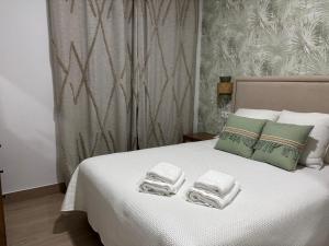 a bedroom with a white bed with towels on it at Mercedes Park in Montilla