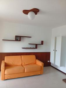 Un sofá naranja en una sala de estar con un techo en Lazaretto, T1, en Mindelo