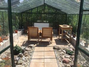 eine Terrasse mit 2 Stühlen und einem Tisch in einem Gewächshaus in der Unterkunft Kleines Ferienhaus in Rangsdorf mit großem Garten - b48672 in Rangsdorf + 14 Fotos