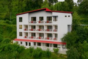 un edificio bianco con tetto rosso di Kafal Pako Resort - Luxury Mountain View Stay in Mukteshwar a Mukteshwar