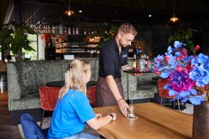 un homme et une fille assis à une table dans un restaurant dans l'établissement Kampeerdorp de Zandstuve - Kindvriendelijke Vakantiepark, à Rheeze 4 autres photos