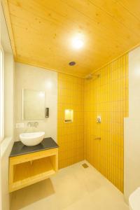 un bagno con un lavandino, uno specchio e piastrelle gialle di Kafal Pako Resort - Luxury Mountain View Stay in Mukteshwar a Mukteshwar Altre 79 foto