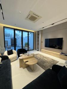 a living room with a table and a large screen tv at شاليهات روح الخبر in Al Khobar