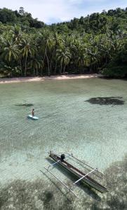 a person on a surfboard in the water next to a dock at Poki Poki - Togian Islands in Bomba