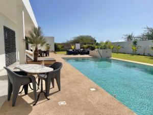 einen Pool mit einem Tisch und Stühlen neben einem Haus in der Unterkunft Villa Blanche in Ngaparou