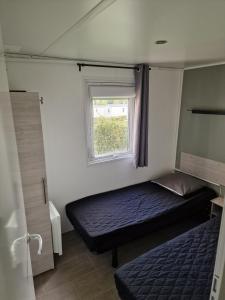 a small bedroom with a bed and a window at TRIGANO Savina 2022 in Litteau