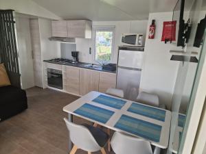 a small kitchen with a table and some chairs at TRIGANO Savina 2022 in Litteau