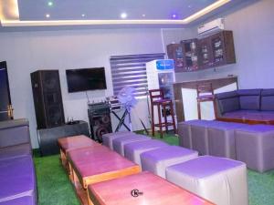 a living room with purple furniture and a flat screen tv at Royal Dean Hotels & Suites in Mama