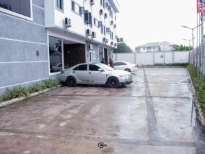 a white car parked in a parking lot next to a building at Royal Dean Hotels & Suites in Mama