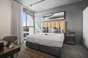 a bedroom with a large bed and a desk at The Capital Boardwalk in Gqeberha