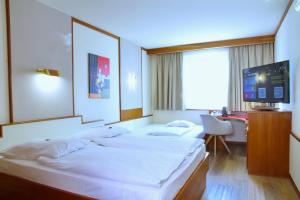 una camera d'albergo con due letti e una tv di Vienna Sporthotel a Vienna Altre 82 foto