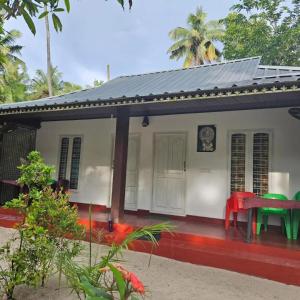 马拉利库兰Marari Aleena Beach Homestay的前面有一张红色桌子的小房子