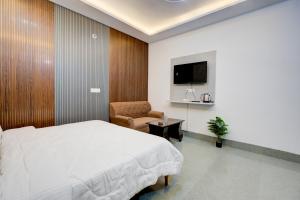 a bedroom with a bed and a chair and a tv at Amara Inn in Greater Noida
