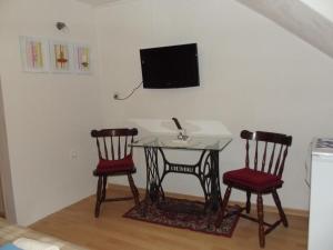 a table with two chairs and a tv on a wall at Studio In Einem Traditionellen Steinhaus, In Baska in Baška